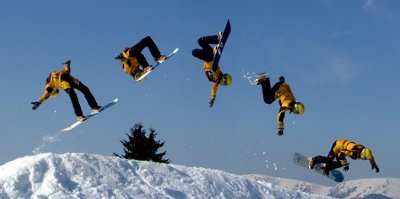 image d&eacute;coup&eacute;e d'un snowboardeur habill&eacute; en jaune et noir qui effectue un back-grab